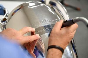 The trophy engravers are etching Manchester City's name on the Champions League trophy.